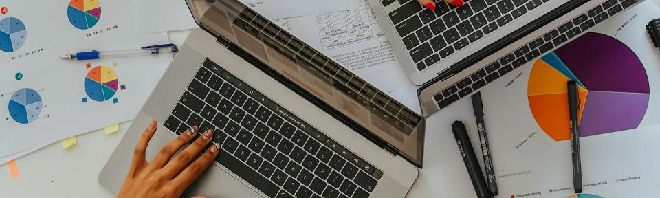 Persons using laptops on table with charts