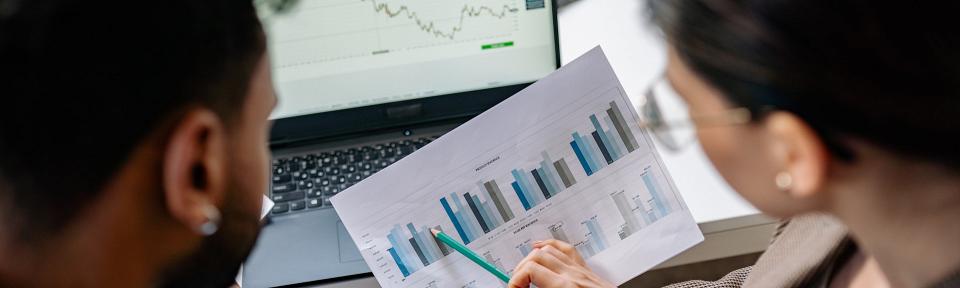 two people discussing graphs on printouts