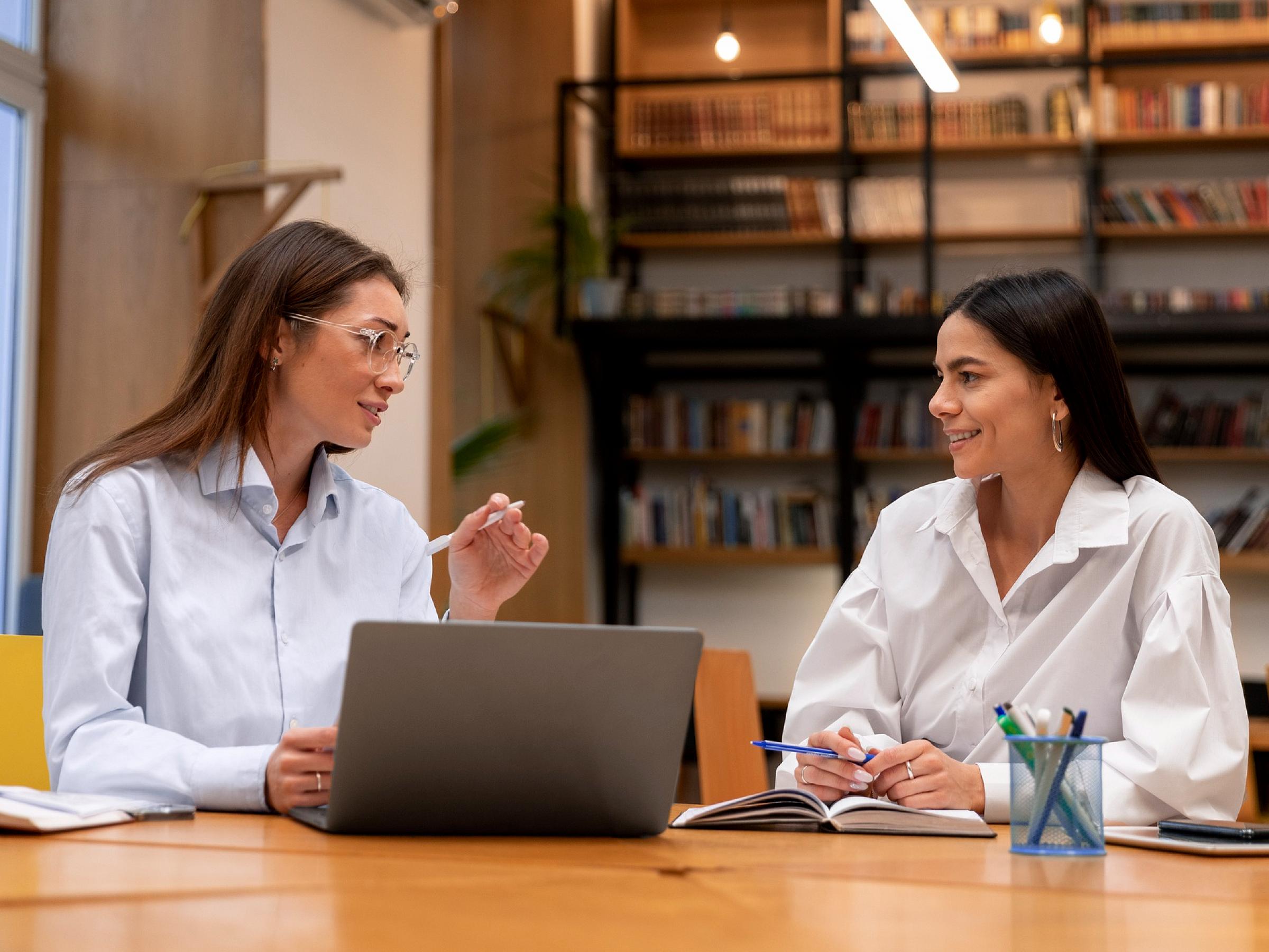 Two women working at a table with a laptop open on it