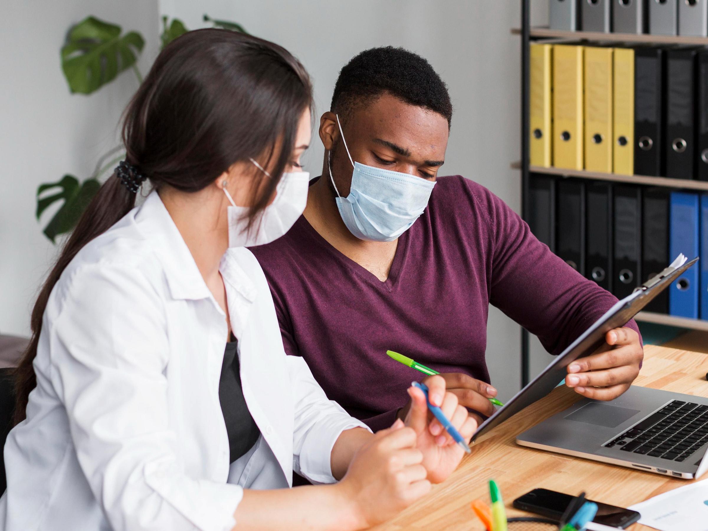2 medical professionals discussing information on a clipboard